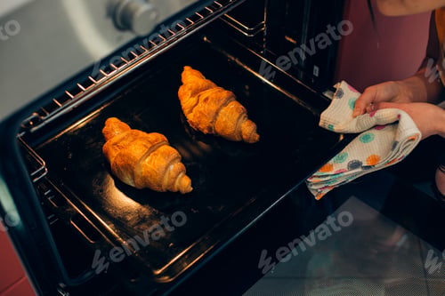 Preview: Close Up Of Unrecognized Person Holding A Towel While Taking A Baking Pan With Delicious Croissants