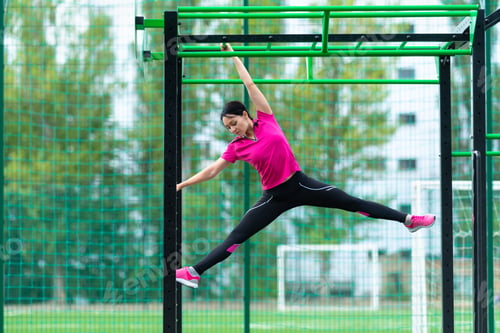 Preview: Fit Sporty Young Woman Working Out On A Parallel Bar At An Open Air Gym In An Urban Park In A