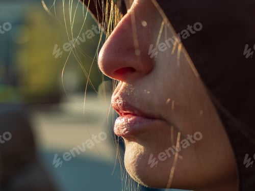 Preview: Young Woman With Beautiful Face In Dark Hood Poses In Front Of Camera In Front Of Sunlight. Thin
