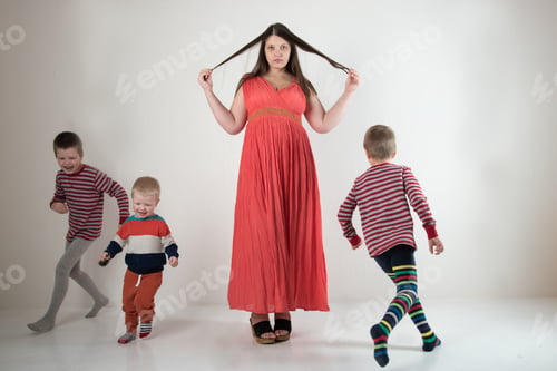 Preview: A Young Girl In A Pink Dress Plays With The Growth Of Her Children. Cute Little Boys In Colorful