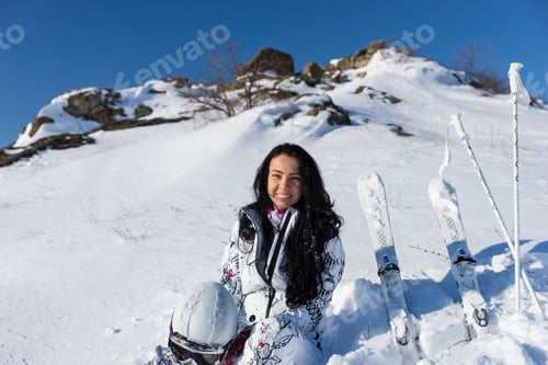 Preview: Waist Up Portrait Of Smiling Young Woman With Long Dark Hair Holding Helmet And Sitting On Snow