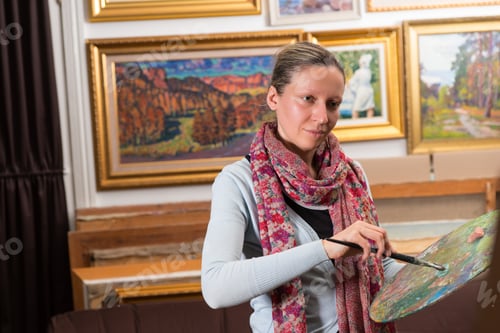 Preview: Professional Female Painting In A Gallery Holding A Colorful Artists Palette And Paintbrush In Her