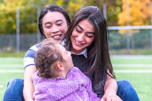Preview: Happy Mixed Family Hugging In A Park. Parents Hugging Their Autistic Daughter.