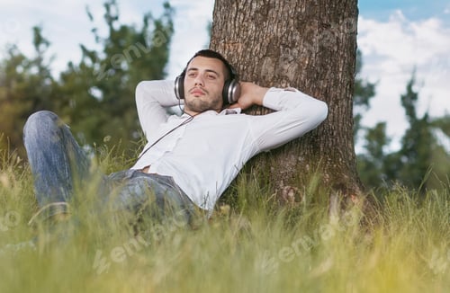 Preview: Young Man Listen Music - Enjoy - Repose In Grass. Guy Leaning Against A Tree Relaxing - Resting