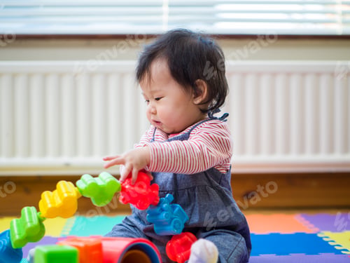 Preview: Adorable Baby Girl Sitting On Play Mat And Playing Toy At Home