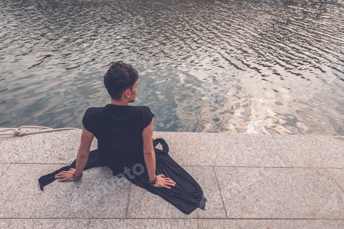 Preview: Young Handsome Asian Model Dressed In Black Tunic Sitting By An Artificial Basin
