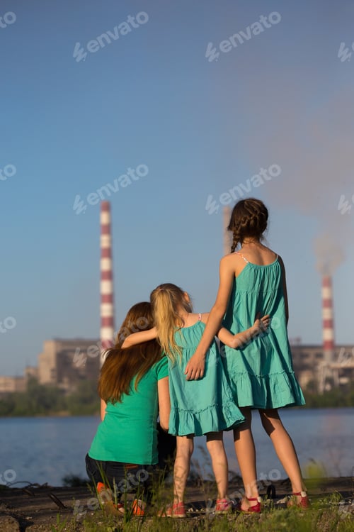 Preview: Care Future Concept. Young Mother With Her Kids Are Looking At The Chimney-Stalks Polluting An Air