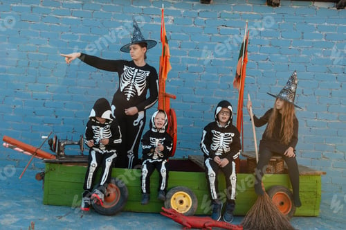 Preview: Cute Family In Skeleton Costumes For Halloween Celebrations Are Playing Pirates On Wooden Sailing