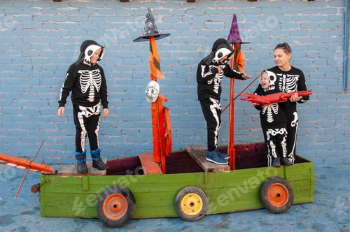 Preview: Happy Friendly Family In Carnival Costumes, Boys And Young Mothers Play On Pirate Ship. Black Suit
