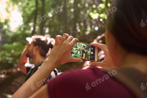 Preview: Young Woman Uses Both Hands To Take A Portrait Photo Of A Young Man Standing Near Trees