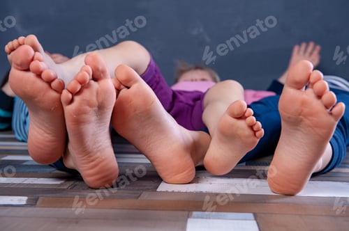 Preview: Three Children Are Sitting On Floor In Room And Are Going To Do Gymnastics. Legs And Feet Of Kids