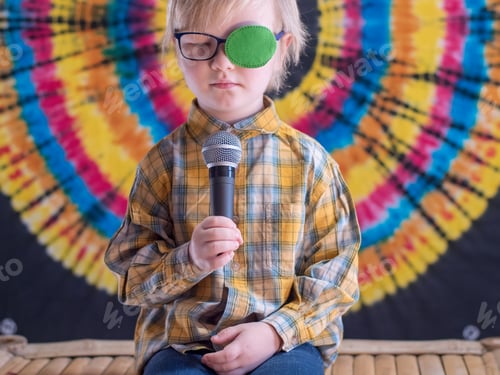 Preview: Portrait Of Funny Child In New Glasses With Green Spot To Correct Strabismus And Microphone