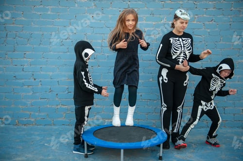 Preview: Cute Children Dressed Up To Celebrate Halloween In Skeleton Costumes Jumping On Trampoline. Boys