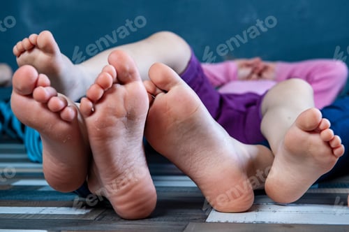 Preview: Three Children Are Sitting On Floor In Room And Are Going To Do Gymnastics. Legs And Feet Of Kids
