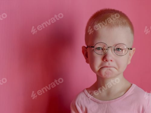 Preview: Portrait Of Funny Child In A Pink T-Shirt In New Glasses Is Playing With Computer Tablet On Pink