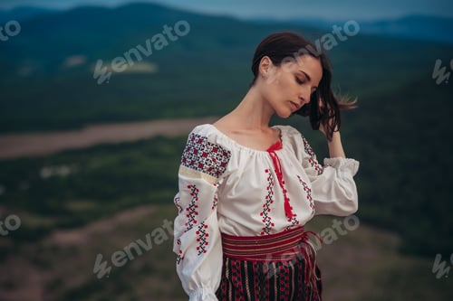 Preview: Attractive Woman In Traditional Romanian Costume On Mountain Green Blurred Background. Outdoor