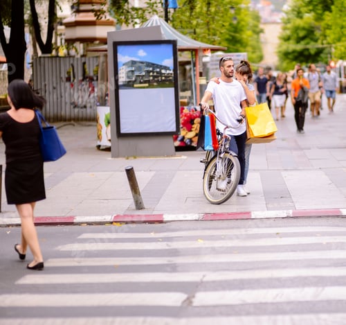 Preview: Beautiful Happy Couple Pushing Bicycle In The City And Holding Shopping Bags. Urban Shopping