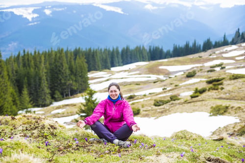 Preview: Young Caucasian Woman Sitting In Yoga Pose In Mountains