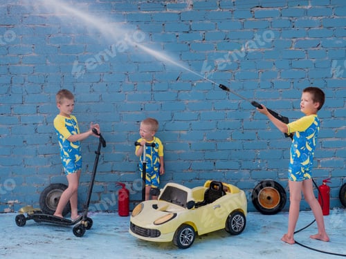 Preview: Funny Children In Boys' Bathing Suits Posing In Front Of Camera With High-Pressure Car Wash And Toy