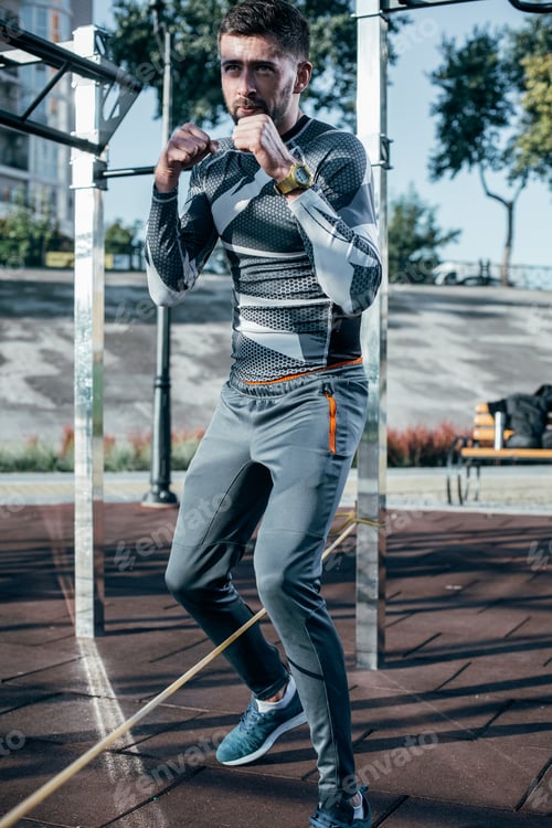 Vista previa: Slim Attractive Sportsman In Comfortable Clothes Jumping Over The Rope At Sports Ground While