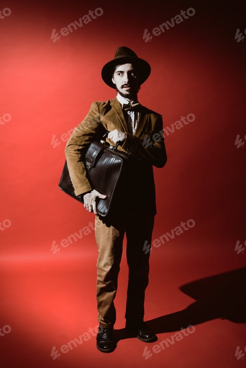 Preview: Man In Suit Posing In Studio With Suitcase In Hands