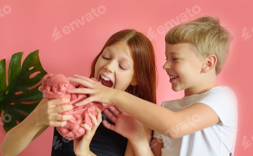 Preview: Cute Blonde Boy And Red Hair Girl Playing With Hand Made Slime On Pink Background