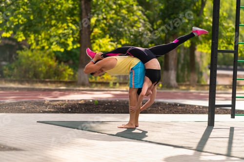 Preview: Young Couple Practicing Acrobatic Yoga With The Young Woman Doing The Splits Over A Mans Back In An