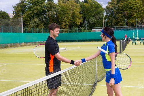 Preview: Two Young Tennis Players Shaking Hands Over The Net Wearing A Sportswear On A Court Outdoor In