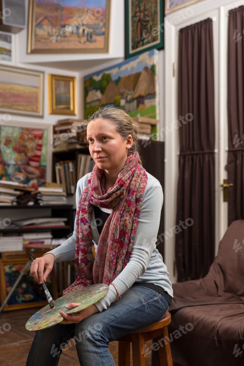 Preview: Thoughtful Female Painter Looking At Pictures In A Gallery Holding A Colorful Artists Palette And