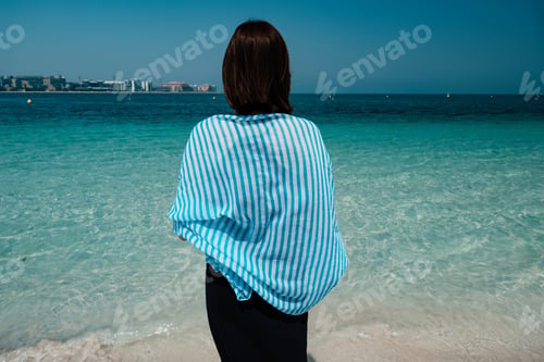 Preview: Back View Of A Woman Walking Towards The Sea In Palm Jumeirah, Dubai. A Woman In A Scarf And Dress
