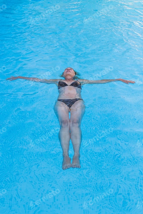 Preview: Top View Of A Woman In Bikini Floating On Her Back In A Swimming Pool