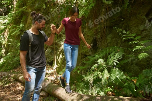 Preview: Young Man Is Helping A Young Woman Walk Over A Fallen Tree By Holding Her Hand And Guiding Her Path