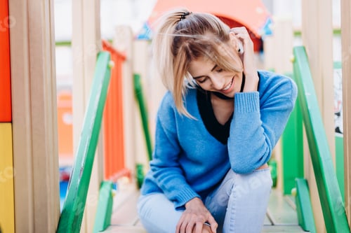 Preview: Blonde Woman Wearing In Blue Sweater Sitting And Looking Down With Smile