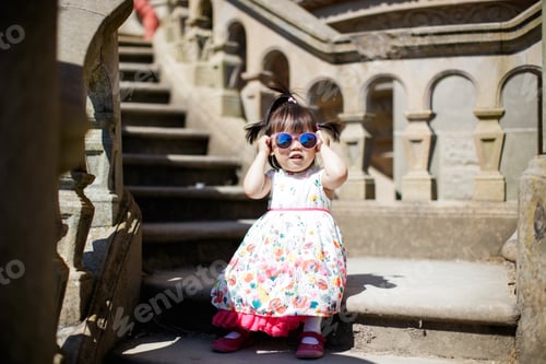 Preview: Baby Girl Wearing Sunglasses Sitting On An Old Staircase