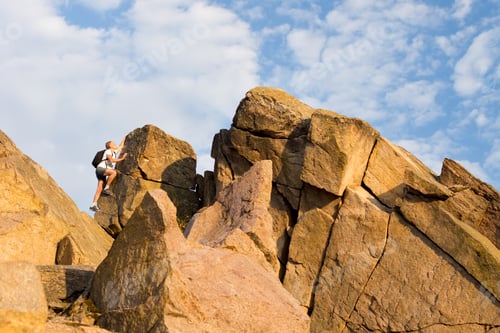 Preview: Man Climbing A Rocky Mountain Peak Wearing A Backpack Enjoying An Active Summer Vacation In Nature