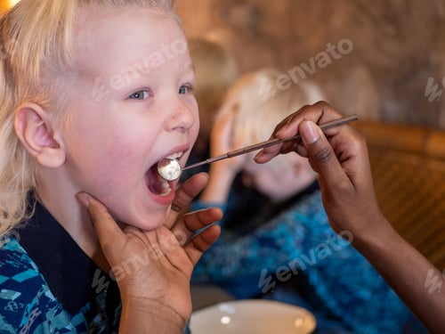 Visualização: Mulher afro-americana vestindo dentista de jaleco branco examina garoto loiro na clínica da vila. DA CRIANÇA