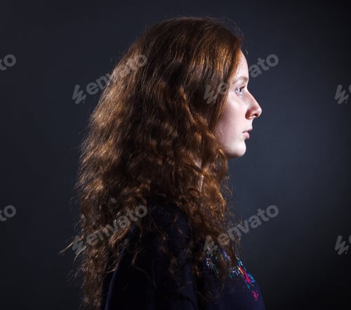 Preview: Portrait Of Young Woman With Red Hair In Profile Against A Dark Background.