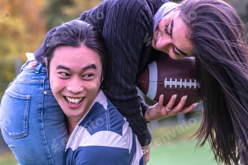 Preview: Couple In Park With American Football. Couple Playing American Football. Couple Playing Rugby