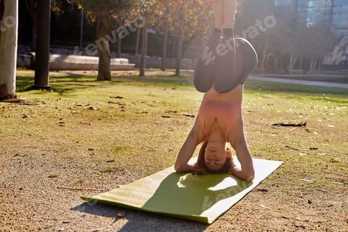 Preview: Young Woman Does A Supported Half Head Stand Yoga Pose Int He Park On A Bright Sunny Day