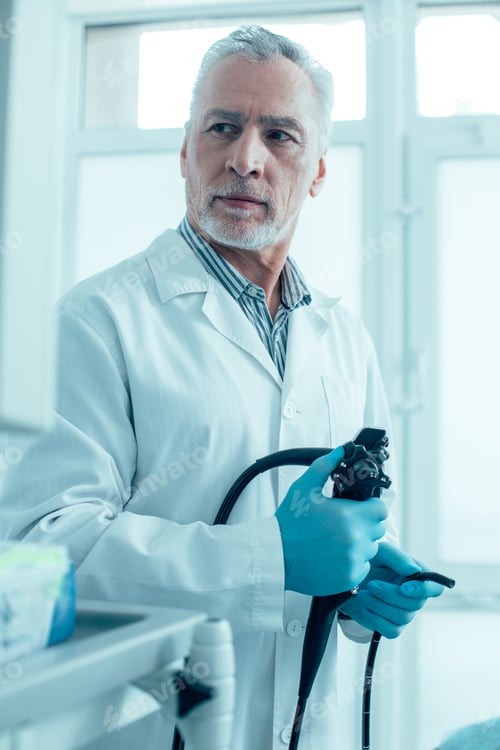 Preview: Medical Worker In Rubber Gloves Holding An Endoscope And Turning To The Screen