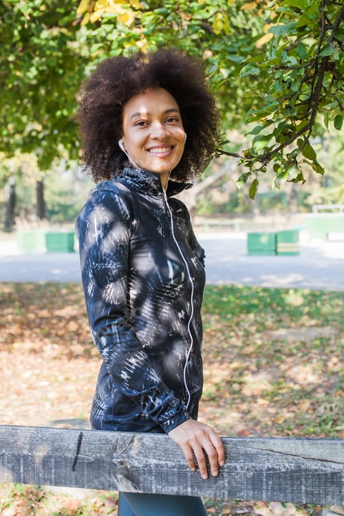 Preview: Attractive Sporty Woman Relax After Training Listening Music At Park, Leaning On Wooden Fence In