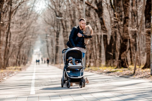 Preview: A Young Family Walk In The Park In The Spring With A Toddler In A Stroller. Happy Parents