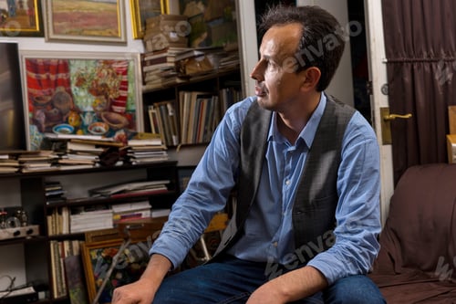 Preview: Portrait Of Male Artist Sitting Looking Trough His Studio With A Paint Brush And Rag In His Hand