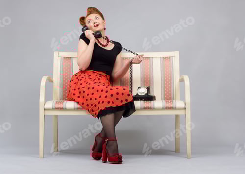 Preview: Beautiful Woman In The Style Of Pin-Up Emotionally Talking On The Phone Sitting On The Couch.