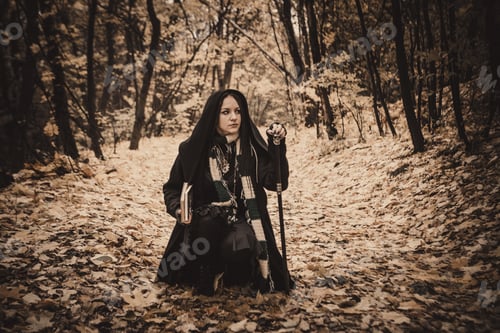 Preview: Charming Lady With Dreadlocks Wearing Black Mantle With Books Standing By The Old Tree In The