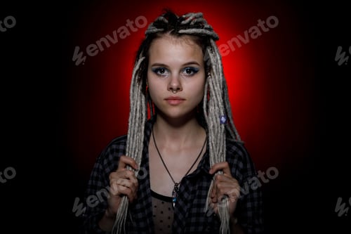 Preview: Portrait Of A Young Woman With Dreadlocks And Piercings In Colored Lighting. Modern Hairstyle Style.