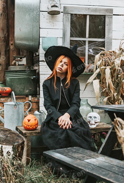 Preview: A Girl In A Witch Costume Having Fun At A Halloween Party On The Decorated Porch