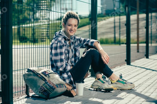 Preview: Smiling Woman Relaxing Outdoors with Backpack and Coffee