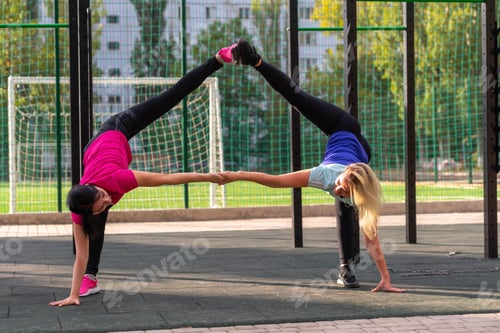 Preview: Two Young Gymnasts Doing Synchronised Yoga In A Team Pose With Touching Hands And Feet At An
