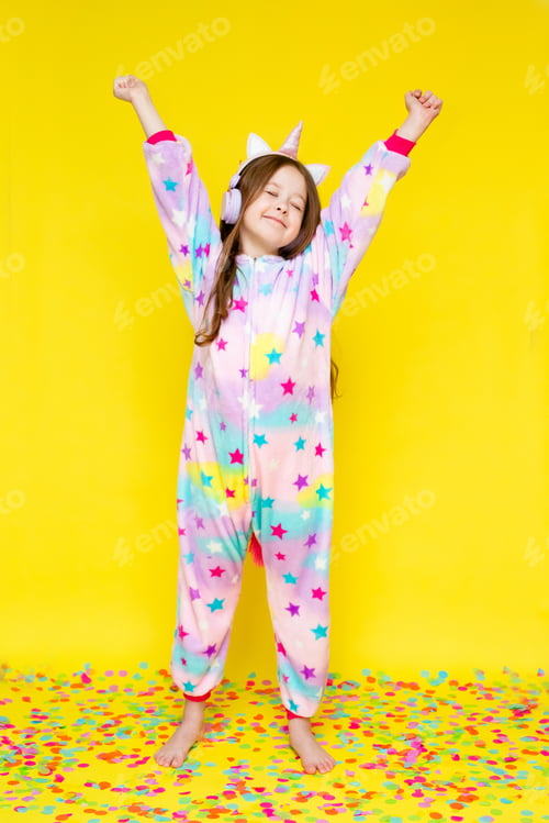 Preview: Little Girl With Long Hair Wearing A Kigurumi And Headphones In The Shape Of A Unicorn Is Happy